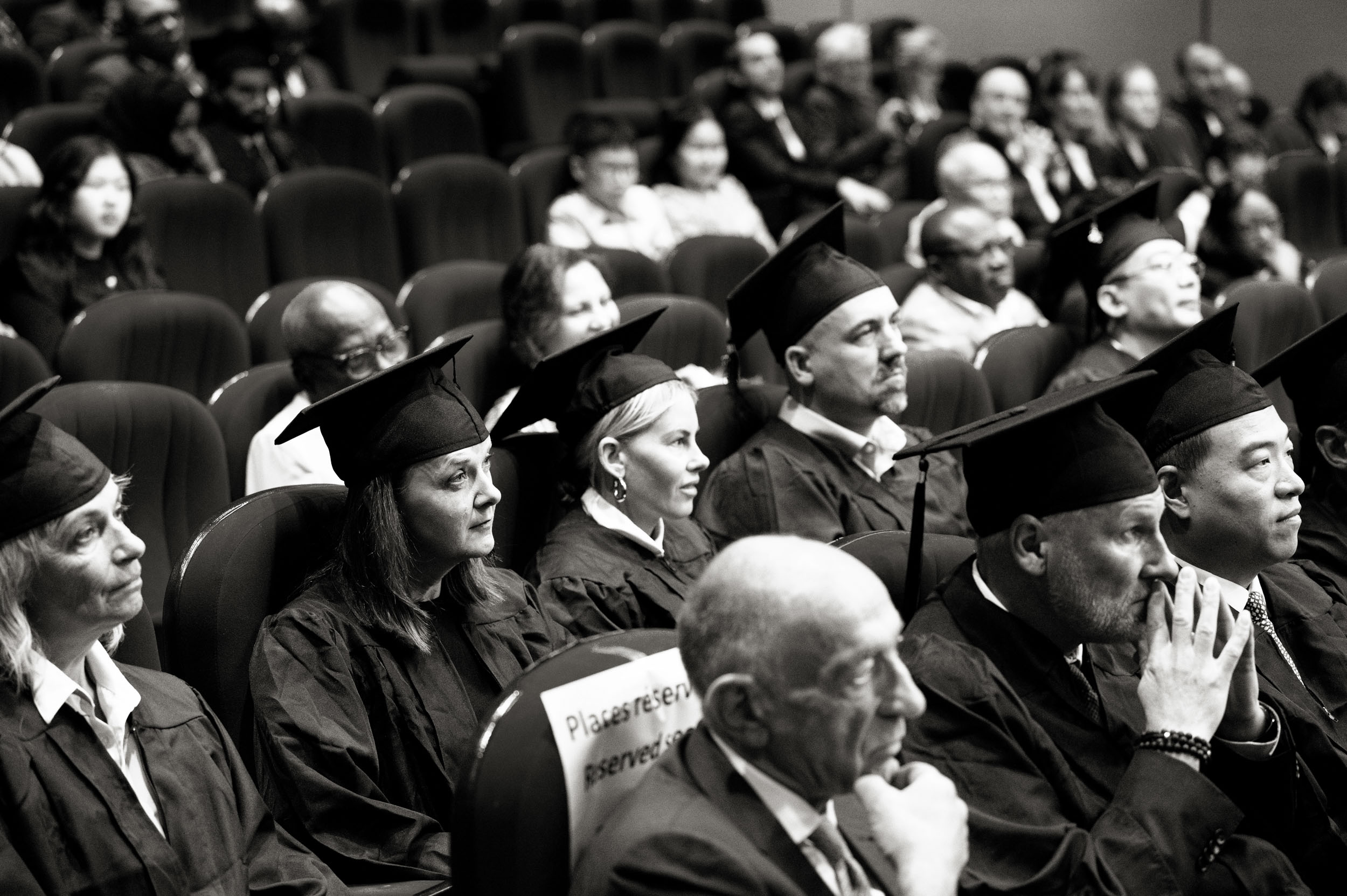 Des diplômés avec leur toque écoutent un discours